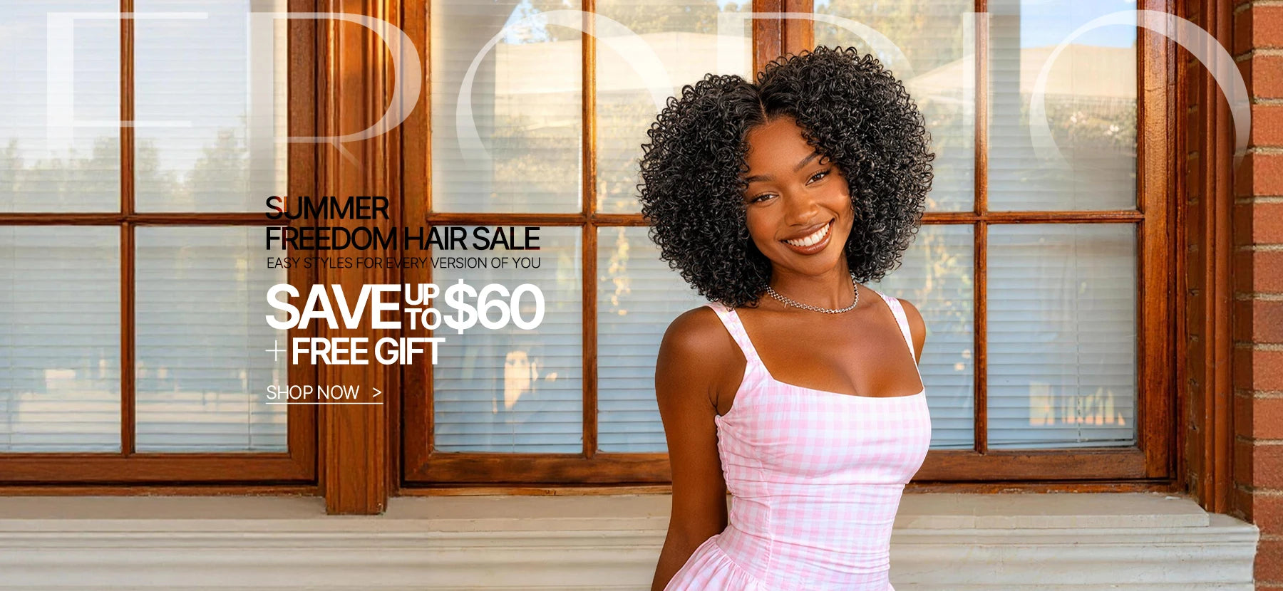 Woman in a pink dress standing in front of a window with an advertisement for a hair sale.